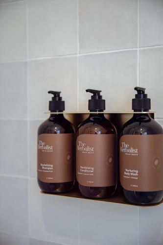 a group of four bottles of soap on a shelf at Sunnymead Hotel in Aireys Inlet