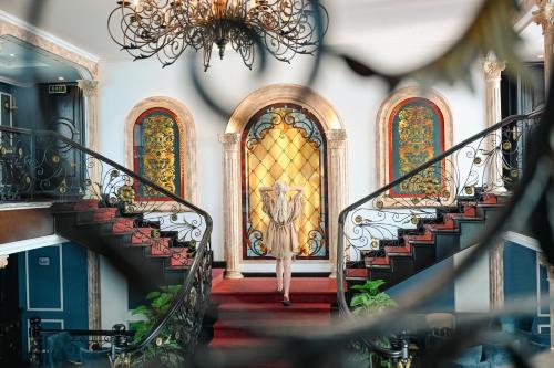 a woman walking down the stairs in front of a door at Le Theatre Cruises - Wonder on Lan Ha Bay in Ha Long