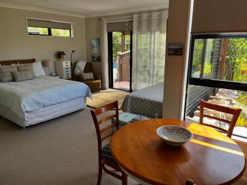 Schlafzimmer mit einem Bett, einem Tisch und einem Bett in der Unterkunft Abel Tasman Sands BnB in Marahau