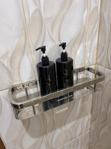 a couple of black bottles on a shelf on a wall at AW Lor House - Yogyakarta in Sleman