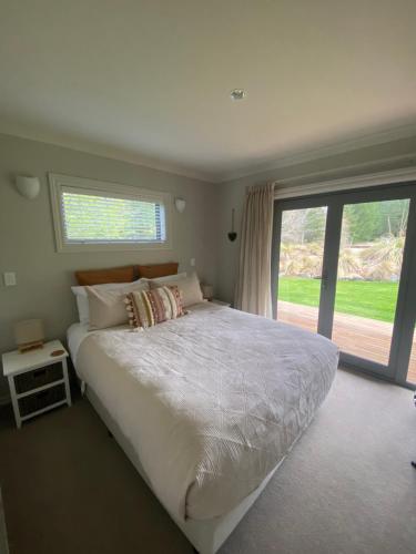 a bedroom with a large bed and a large window at Foehn Cottage in Twizel