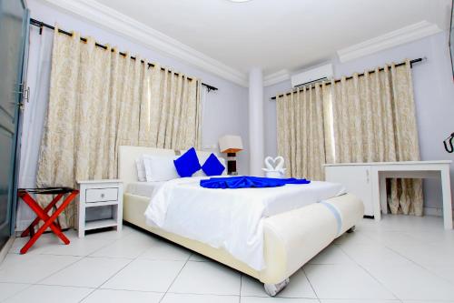 1 dormitorio blanco con 1 cama grande con almohadas azules en Hotel Galilée, en Cotonou