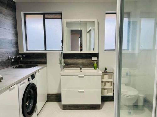 a bathroom with a sink and a washing machine at Beachside spacious unit 9 in Tuncurry