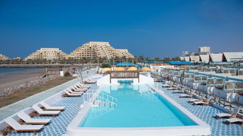 a swimming pool with lounge chairs and a beach at Banan Beach in Ras al Khaimah