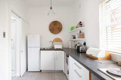a kitchen with white cabinets and a white refrigerator at Shabby Chic in Muizenberg