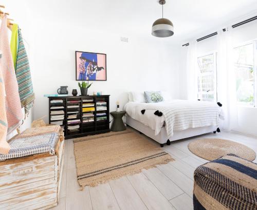 a white bedroom with a bed and a chair at Shabby Chic in Muizenberg