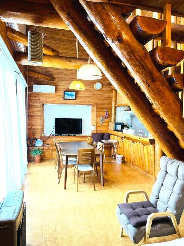 a living room with a table and chairs and a couch at 民泊JOYFUL天然温泉付きログハウス in Shiraoi