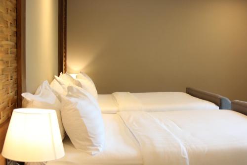 a white bed with white pillows next to a lamp at River Tree Resort in Chiang Khan