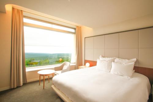 a hotel room with a large bed and a large window at Rockwood Hotel & Spa in Ajigasawa