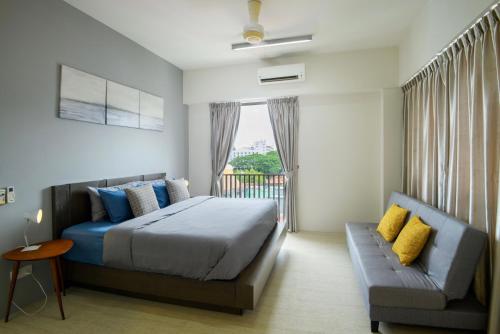 a bedroom with a bed and a couch and a window at By The Sea Beach Front Apartment in Batu Ferringhi