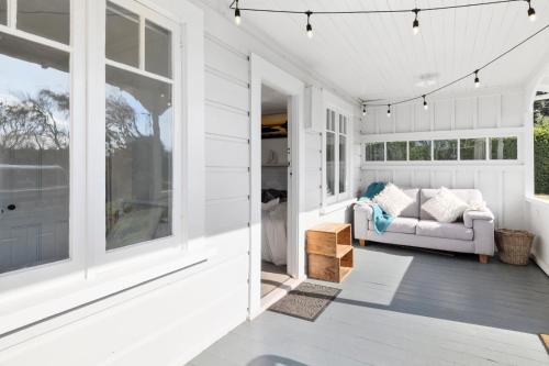 Casa blanca con sofá en el porche en Karitane Cottage - Karitane Holiday Home en Karitane