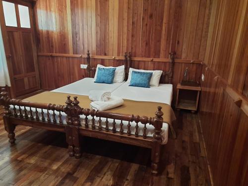 a bedroom with a large bed with blue pillows at Sopanam Heritage Thekkady in Thekkady