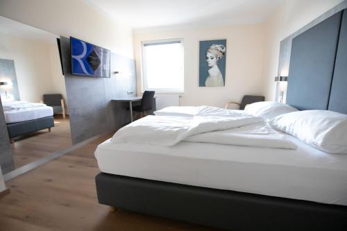 1 dormitorio con 2 camas blancas y escritorio en Das Reinisch Just Rooms en Schwechat