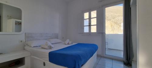 a white bedroom with a bed with a blue blanket at Three Harites in Perissa