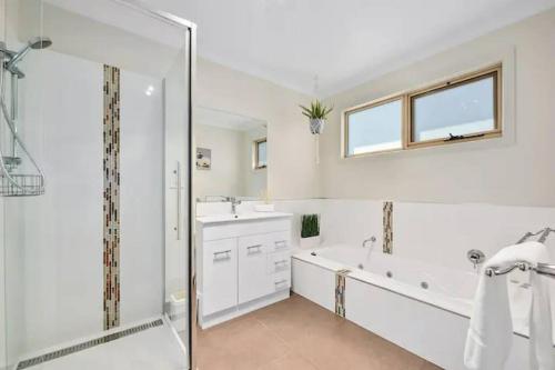 a white bathroom with a tub and a sink at Windbourne House The Ultimate Base in St Helens