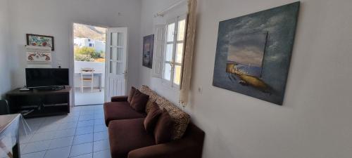 a living room with a couch and a painting on the wall at Three Harites in Perissa