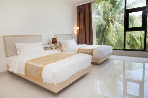 two beds in a white room with a large window at One El Nido Suite in El Nido