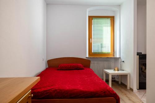 um quarto com uma cama vermelha e um cobertor vermelho em Appartamento Meridiana em Roncone
