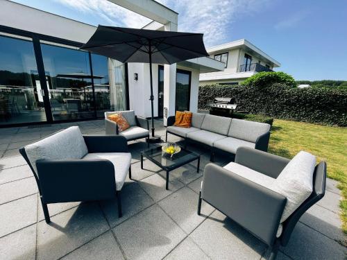 une terrasse avec des canapés et une table avec un parasol dans l'établissement Luxury holiday home in Zeewolde with garden and bubble bath, à Zeewolde