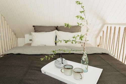 ein Bett mit einem weißen Tisch mit Tassen drauf in der Unterkunft ALNUS KIEMAS in Kampiškiai