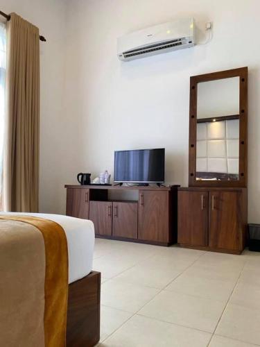 a bedroom with a bed and a dresser with a mirror at Serenity Villa Dambulla in Sigiriya