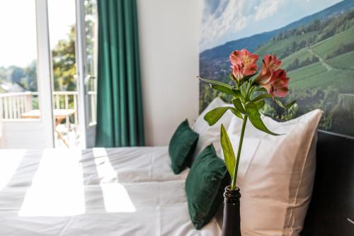 a vase with a flower on a bed with a window at Dormio Wijnhotel Valkenburg in Valkenburg
