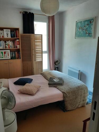 um quarto com uma cama com lençóis cor-de-rosa e uma janela em Chambre hôte Residence sous les pins em Cassis