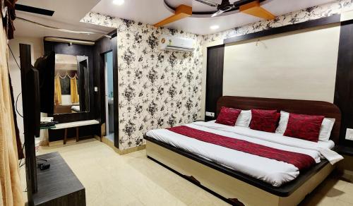 a bedroom with a large bed with red pillows at Hotel Satpura Safari in Pachmarhī