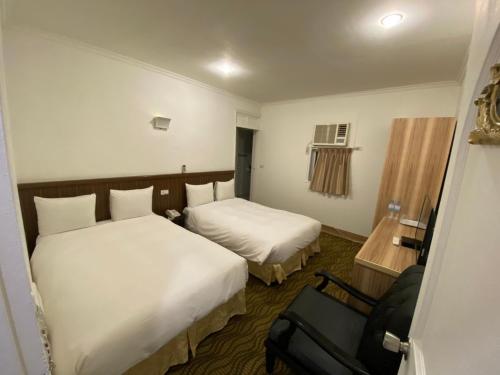 um quarto de hotel com duas camas e uma cadeira em Queens Hotel em Taipei