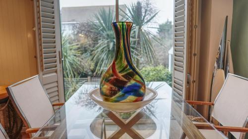 a colorful vase sitting on a glass table at Modern Seaside Townhouse feat Sauna near Brighton in Shoreham-by-Sea