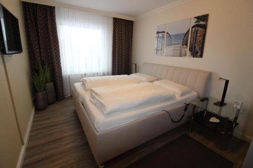 - un lit blanc dans une chambre avec fenêtre dans l'établissement Haus Norderhoog Wohnung 31, à Westerland