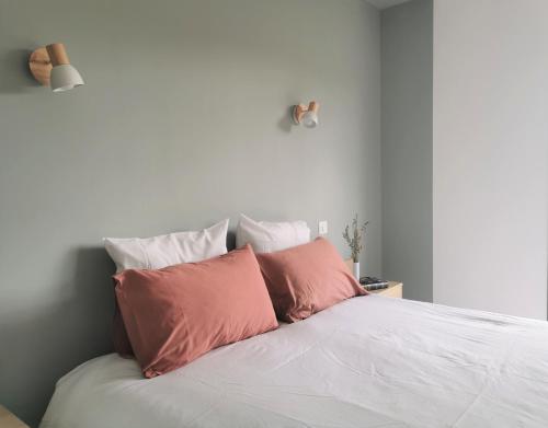 a white bed with two pink pillows on it at Au Jardin des Deux Roches in Prissé