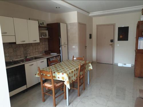 eine Küche mit einem Tisch und Stühlen sowie eine Küche mit weißen Schränken in der Unterkunft Appartamento Marchese in Racalmuto