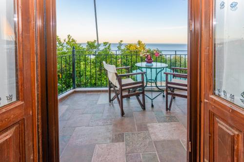a balcony with a table and chairs and the ocean at Eros Pittoresque Retreats - Perfect location, Panoramic Seaview in Koroni
