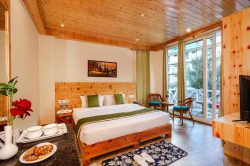 Tripli Hotels Stone House Cottage في مانالي: غرفة نوم بسرير وتلفزيون في غرفة
