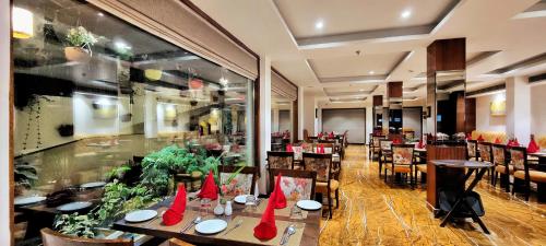 Hotel Royale Retreat - Luxury Hotel In Shimla في شيملا: مطعم عليه طاولات عليها قبعات حمراء