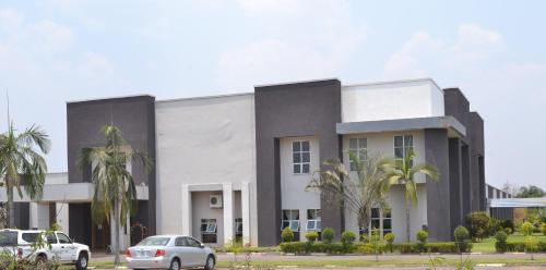 a white building with two cars parked in front of it at Moba Hotel & Convention Centre in Kitwe