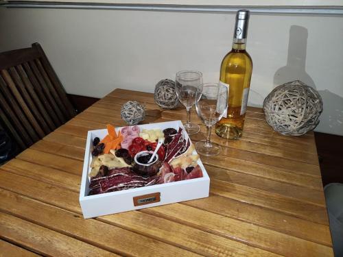 a box of food on a wooden table with wine glasses at Nuit insolite sur l'eau au port de Ouistreham in Ouistreham
