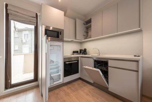 a kitchen with white cabinets and a large window at Sea Stories Apartments Varna in Varna City