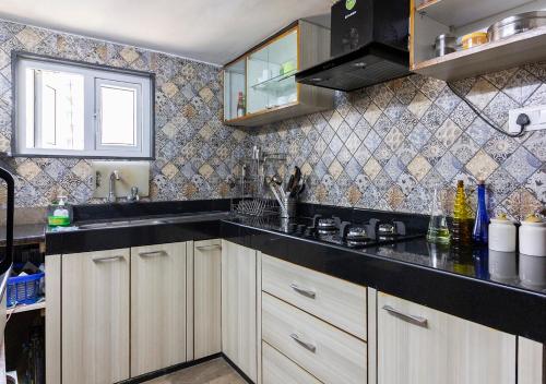 a kitchen with white cabinets and a black counter top at Neelam Bed & Breakfast in Kolkata
