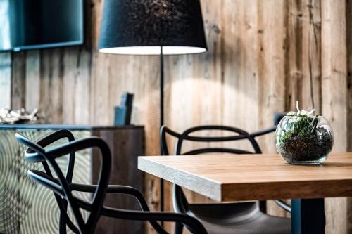 a table with chairs and a lamp with a plant on it at ALMMONTE PRÄCLARUM SUITES Design Hotel in Wagrain