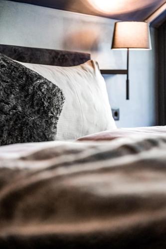 a bed with a pillow and a lamp in a room at ALMMONTE PRÄCLARUM SUITES Design Hotel in Wagrain