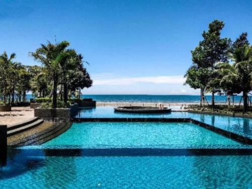 ein Schwimmbad mit dem Ozean im Hintergrund in der Unterkunft vitamin SEA Timurbay Residence in Kuantan