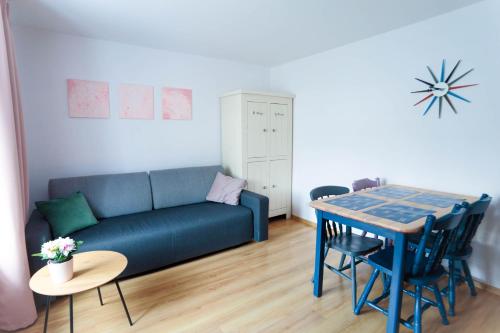 een woonkamer met een blauwe bank en een tafel bij Apartament Rosiczka in Duszniki Zdrój