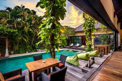 a patio with a table and a swimming pool at Lautan Kupu - Kupu Villas in Canggu