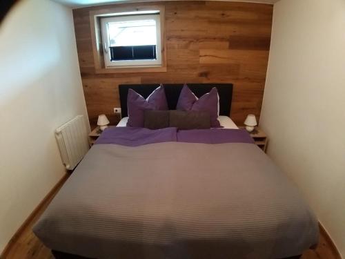 - une chambre avec un lit doté d'oreillers violets et d'une fenêtre dans l'établissement APPARTEMENT Michael, à Tamsweg