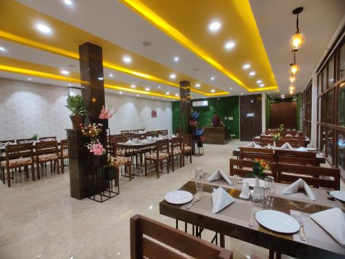 a restaurant with tables and chairs in a room at Hotel Aurelia Pearl in Patna