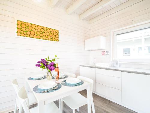 a white kitchen with a white table and chairs at Holiday House Sarbinowo in Sarbinowo