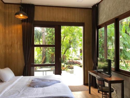 a bedroom with a bed and a desk and a window at Likita Resort in Ban Phe