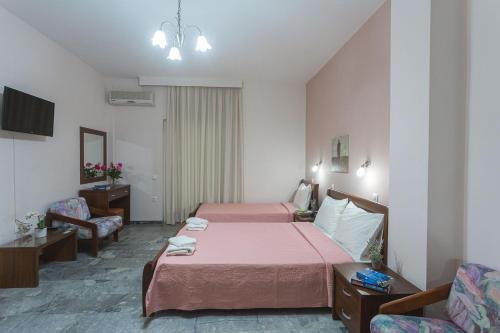 een slaapkamer met een bed, een bank en een stoel bij Remvi Hotel - Apartments in Stoupa
